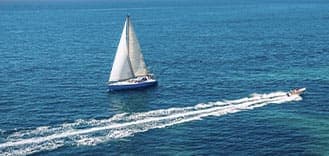speedboat passing sailboat